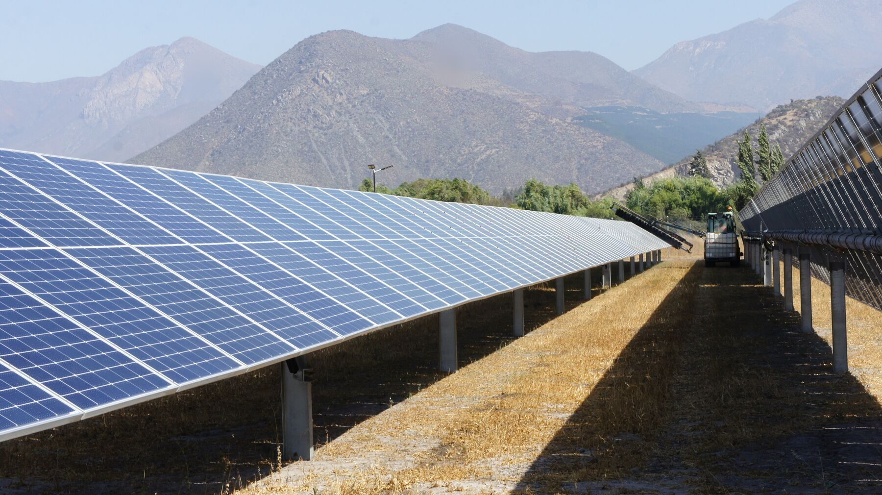 Rows of solar panels at a completed project, mountains behind